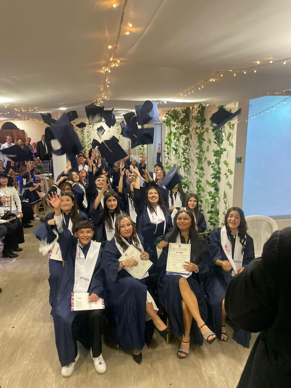 Estudiantes lanzando el birrete en la ceremonia de graduación de inglés