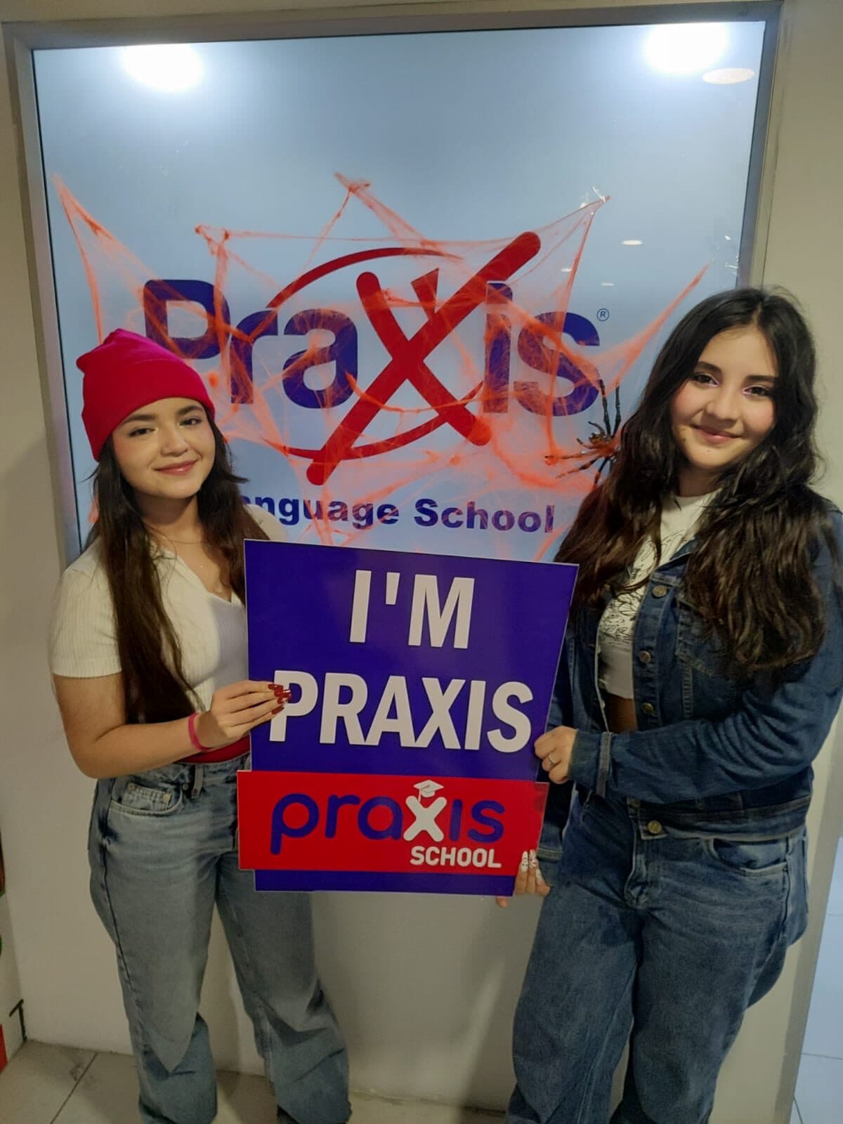 Dos estudiantes con el cartel I'm Praxis en la sede