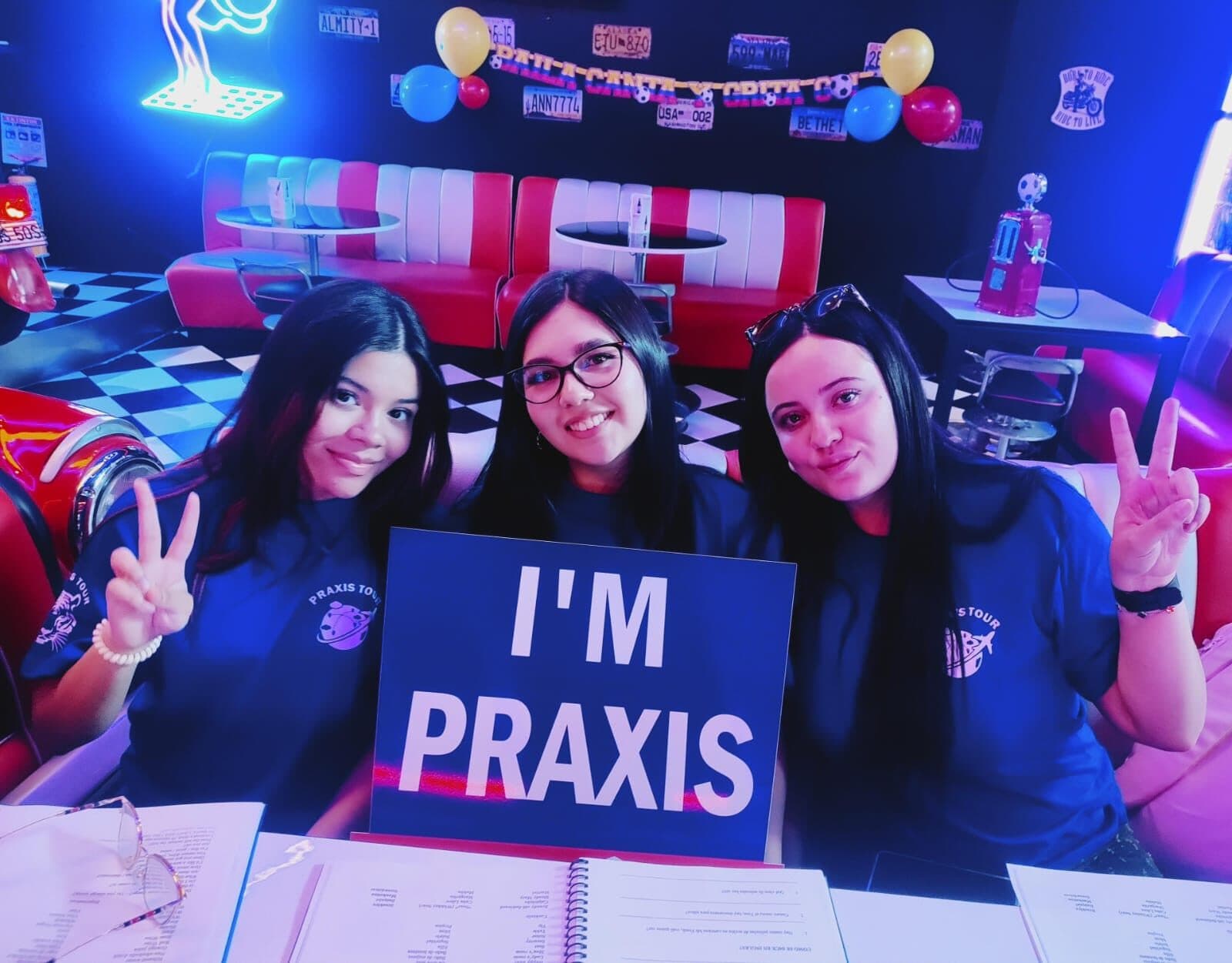 Tres estudiantes sonrientes con el cartel I'm Praxis